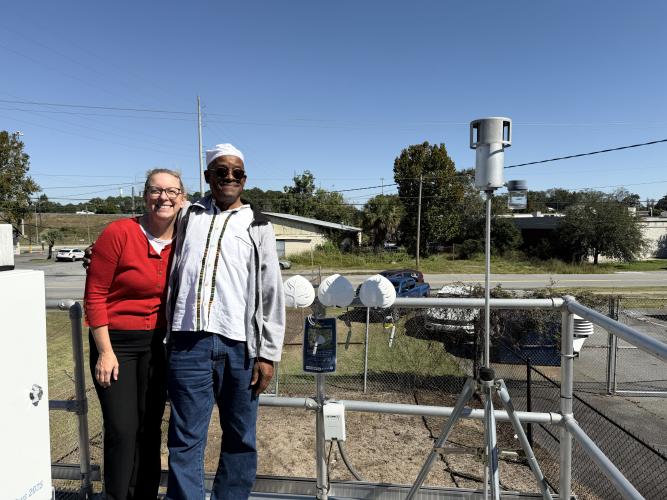 IPaT researcher Jill Gambill is pictured with David Shabaka, Harambee House, in Savannah. Behind them are three newly designed air monitors (white plastic leaf enclosures) waiting for installation in different locations.
